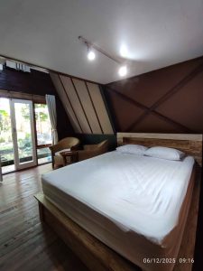 Interior kamar tidur kayu segitiga dengan tempat tidur dan balkon di Vava Brighton.