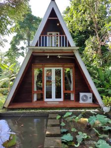Rumah kayu segitiga 2 kamar tidur di lingkungan alami.