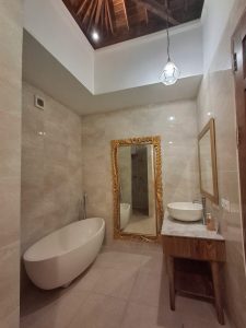 Kamar mandi modern dengan bathtub dan cermin besar di villa Umalas.