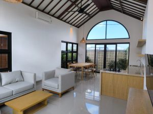 Interior ruang tamu villa dekat Canggu dengan sofa dan jendela besar.