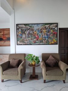 Ruang tamu villa mewah dengan dua kursi nyaman dan lukisan besar di dinding.